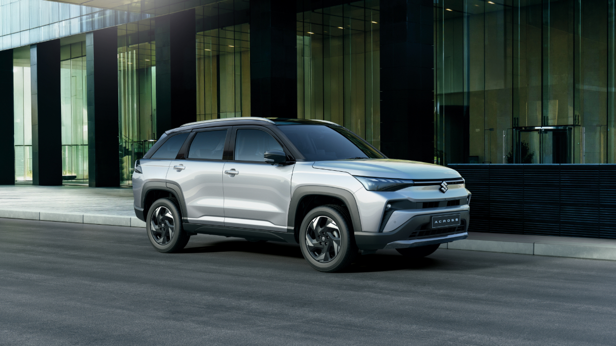 Silver Suzuki Across SUV Parked Outside Modern Glass Building